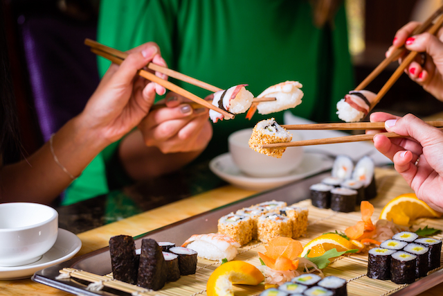 箸で寿司を食べる人たち