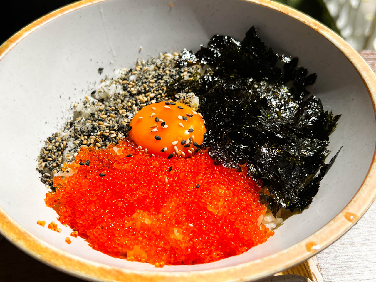 ご飯の上にとびっこ、韓国海苔、ごま、卵黄をのせた丼