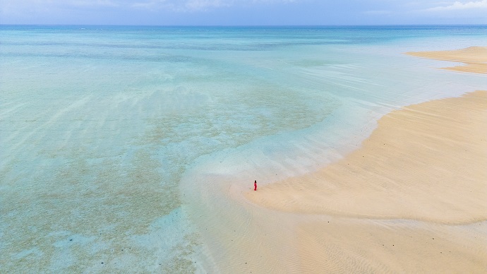 ユニの浜を歩く女性を上空から撮影している様子