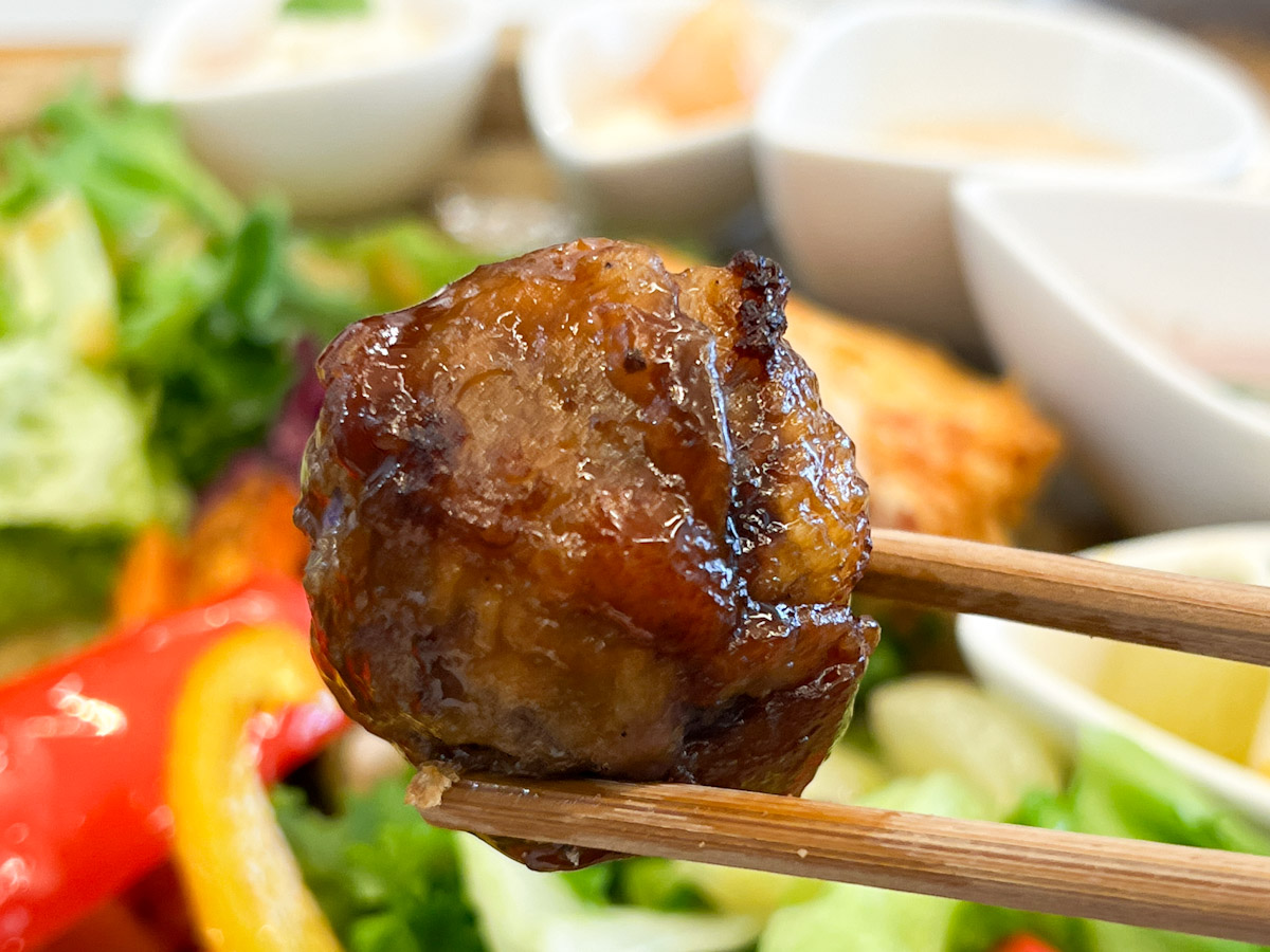箸で持ち上げた「ぶどうの定食」の「ピオーネの肉巻き～酢豚風～」
