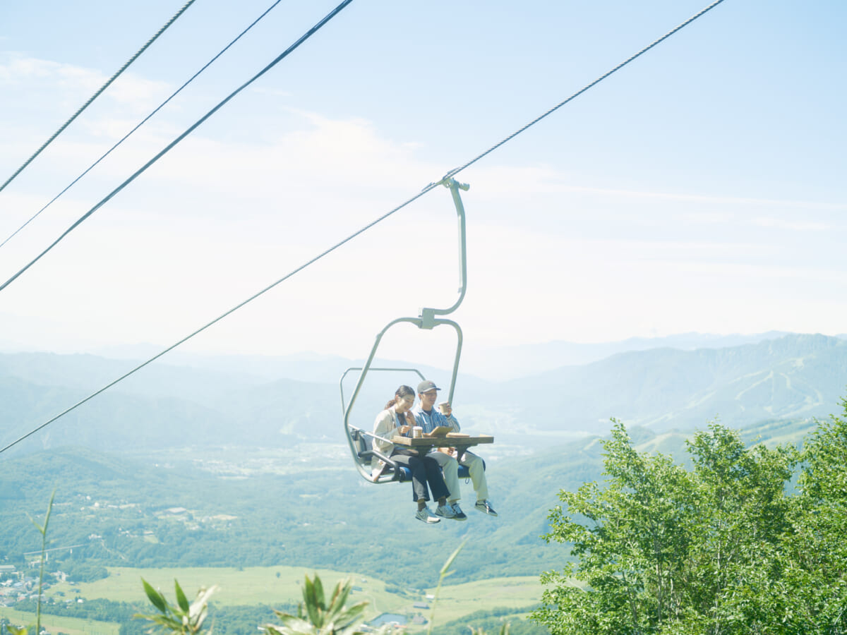 朝食を山頂に向かうリフトの上でいただく「Breakfast in the sky」体験中のカップル