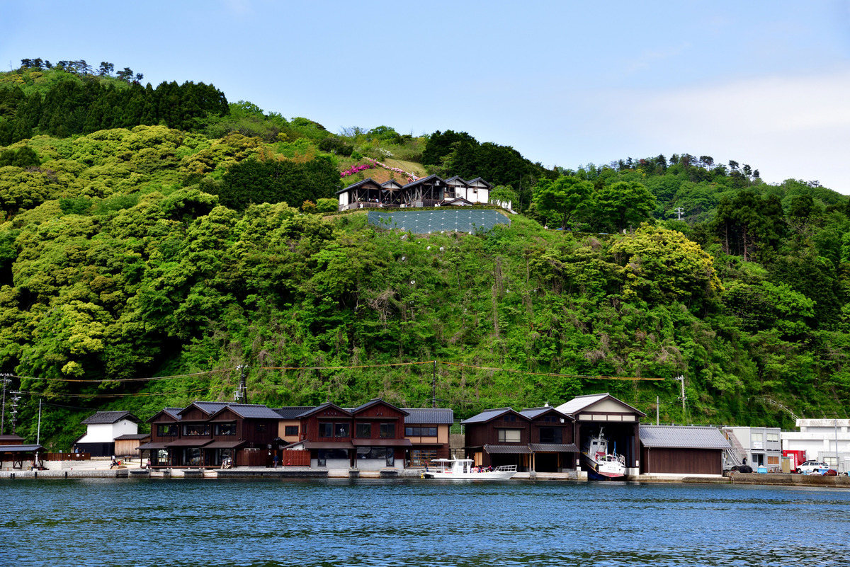 伊根の舟屋の風景　丘の上に見えるのが「道の駅 舟屋の里 伊根」　Photo by PIXTA